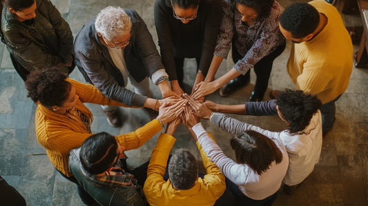 A group of people holding hands in prayer, offering support and comfort to one another during a time of grief.